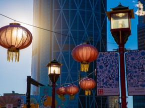Lanterns and lights light up in morning light with The Bow tower as a backdrop in Calgary's Chinatown on Wednesday, November 24, 2021.