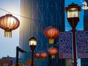 Lanterns and lights lit up in morning light with The Bow Tower as a backdrop in Calgary's Chinatown on Wednesday, November 24, 2021.