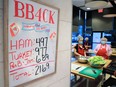 A sign lists the day's lunches as volunteers prepare them at Brown Bagging for Calgary's Kids on Monday, November 15, 2021.