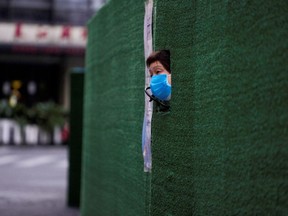 FILE PHOTO: A resident looks out through a gap in the barrier at a residential area during lockdown, amid the coronavirus disease (COVID-19) pandemic, in Shanghai, China, May 6, 2022. REUTERS/Aly Song/File Photo