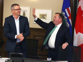 Premier Jason Kenney waves to applause from Finance Minister Travis Toews and other members of the UCP cabinet prior to a meeting in Calgary on May 20, 2022.
