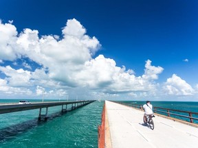 A man cycles on the Old Seven Mile Bridge near Marathon, Fla. The modern Seven Mile Bridge, on the left, is the longest of 42 bridges over water that comprise the Florida Keys Overseas Highway. Laurence Norah/Florida Keys News Bureau