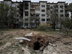 Local residents walk in front of an apartment building destroyed in a missile strike, amid Russia's invasion of Ukraine, in Bakhmut, Ukraine June 13, 2022.