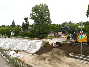 City of Calgary crews work near Memorial Dr. and 3 St. W on removing part of a berm constructed to stop rising waters from the Bow River in the community of Sunnyside on June 16, 2022.
