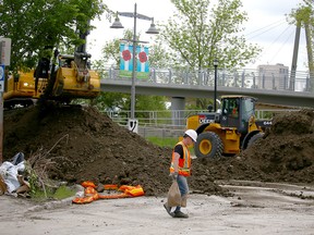 City of Calgary crews work near Memorial Dr. and 3 St. W on removing part of a berm constructed to stop rising waters from the Bow River in the community of Sunnyside on June 16, 2022.