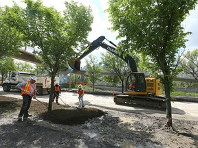 Crews work on the cleanup and repair of areas where a berm was constructed on Memorial Drive near 3 St NW in Calgary on Sunday, June 19, 2022. Memorial Drive is scheduled to be open for traffic by Monday morning.