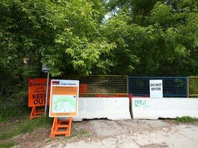 Signs warning residents and pathway users of possible dangers at the base of McHugh Bluff on 3 Ave NW in Calgary on Wednesday, June 22, 2022.