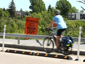Signs warning residents and pathway users of possible dangers at the top of McHugh Bluff on Crescent Rd NW in Calgary on Wednesday, June 22, 2022.