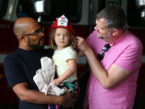 Rishi Agarwal, Tara Agarwal, 3, and Daniel Langdon, all from Toronto pose at Firehall 6 in Calgary on Tuesday, June 28, 2022. The fire crew made the decision to transport Tara to hospital early Sunday morning, June 26, 2022, following a critical medical event.