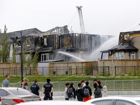 Firefighters pour water on homes badly damaged in a blaze in the northwest community of Evanston on Friday, June 3, 2022.