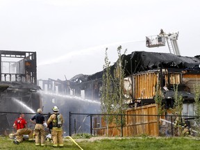 Firefighters pour water on homes badly damaged in a blaze in the northwest community of Evanston on Friday, June 3, 2022.