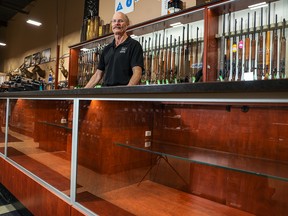 James Bachynsky, owner of the Calgary Shooting Centre, is shown behind empty cases that would normally be displaying handguns on Friday, June 3, 2022.