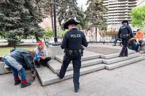 Calgary police officers speak with people in Olympic Plaza.