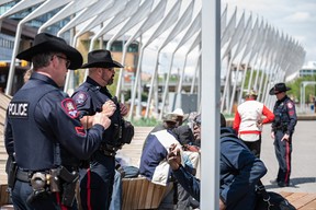 Calgary police officers speak with a group of people in East Village.