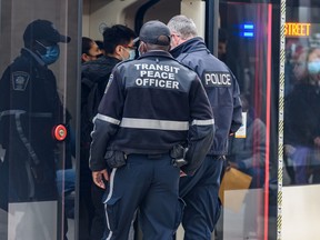 A transit peace officer and a member of the Calgary Police get on a CTrain at City Hall station on Monday, February 28, 2022.