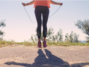 Girl in sportswear and sneakers jumping with a skipping rope on in the summer of the sea background, toned image.  Getty Images/iStockphoto