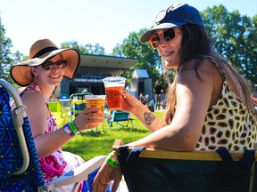 Friends Audra Richards, left and Ashley Yeoman enjoy beer while watching the main stage on the opening night of the Calgary Folk Music Festival, Thursday, July 21, 2022. It is the first year that the festival has been granted an all-site alcohol licence.