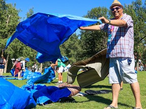 Former Mayor Naheed Nenshi gets his tarp ready in front of the main stage during the opening night of the Calgary Folk Music Festival on Thursday, July 21, 2022.