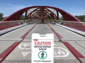 Des panneaux avertissent les cyclistes et les piétons des dommages au pont Peace près du centre-ville de Calgary le dimanche 24 juillet 2022. Plusieurs panneaux ont été brisés, causant des milliers de dollars de dommages.