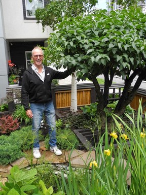 Peter Taylor, 11th Street Gardens owner, pictured in the front yard of his two, vintage inner-city homes. The tree-lilac could well be as old as the homes which were built in 1912. Photo, Bill Brooks