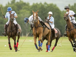 Rob Peters, left, chases a ball at the Black Diamond Polo Club in Calgary on Thursday, Aug. 20, 2015.