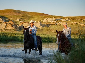 Ty Amen, left, and Ryder Nelson ride their horses in the Milk River after the Writing-On-Stone Rodeo east of Milk River, Ab., on Sunday, July 31, 2022.
