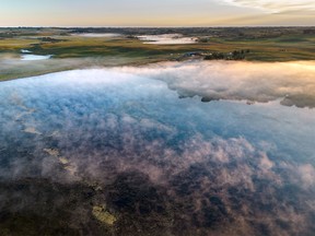 Morning mist rises from a pond west of Airdrie, Ab., on Monday, August 15, 2022.