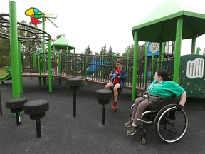Camp Supervisor Keighley Schofield joins Hudson Litsas, 8, at one of the newly constructed inclusive playgrounds at Sandy Beach in Calgary on Wednesday, August 3, 2022. The park is one of 10 recently completed in Calgary and includes wheelchair ramps and other features.
