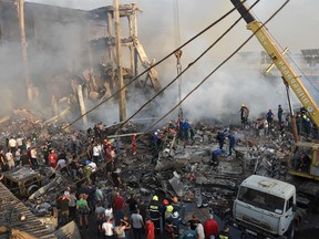Rescue workers and volunteers clear debris as they operate on the site of a retail market in the Armenian capital Yerevan on August 14, 2022, after an explosion sparked a fire, killing one person and injuring 20, according to the emergency situations ministry. - The blast, the cause of which was not immediately known, ripped through the "retail market in Surmalu. According to preliminary information it started a fire. There are victims," the ministry said.