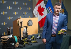 Staff Sgt. Ben Lawson displays the 3D-printed firearms that were confiscated after 66 charges were filed against two men.