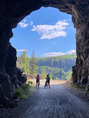 Image of two women cycling through rail tunnels in Myra Canyon near Kelowna, British Columbia, Canada.
