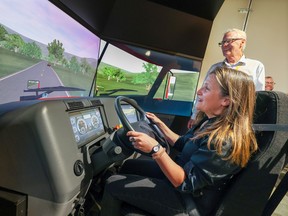Die stellvertretende Premierministerin Chrystia Freeland probiert mit dem Sicherheitsberater von Bison Transport, David Cousins, einen Lkw-Simulator aus, während sie am Mittwoch, den 31. August 2022, das Depot des Unternehmens in Calgary besichtigt.