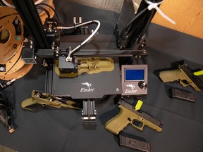 A 3D printer and handguns on display at a Calgary police press conference on Thursday.