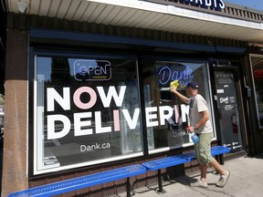 Darren Helkenberd of Dank Cannabis cleans the non-blackout front window of the store on Tuesday, August 9, 2022.