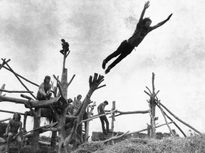 In this Aug. 15, 1969 file photo, rock music fans sit on a tree sculpture as one leaps mid-air onto a pile of hay during Woodstock. To some, the pivotal festival of “peace and music” 53 years ago was an inspiring moment of countercultural community and youthful free-thinking. To others, it was an outrageous display of indulgence and moral decay in a time of war. AP photo, Postmedia files.