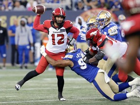 Calgary Stampeders quarterback Jake Maier gets rid of the ball when he is hit by defensive end Jackson Jeffcoat of the Winnipeg Blue Bombers at IG Field in Winnipeg on Thursday, August 25, 2022.