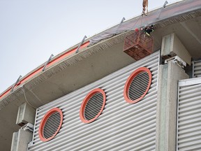 Workers attach netting on the edge of the Saddledome roof Wednesday to catch concrete in areas that may be crumbling.