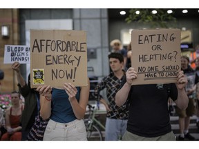 Protesters hold placards during a demonstration against rising energy prices outside Ofgem's headquarters in Canary Wharf on August 26, 2022 in London, England.