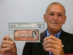 Morris Kosowan from Sylvan Lake, AB shows a rare Canadian two dollar note at a coin show at the Clarion Hotel in Calgary on Saturday, September 17, 2022. The bill is rare because people claimed to see a devil's face in the curls of the Queen's hair, and the mint quickly changed the artwork for future printings.