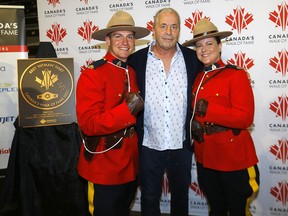 Bret ‘Hitman’ Hart is flanked by RCMP constables J.R. Falzetta and Candace Harris at the Victoria Pavilion in Calgary on Monday, Sept. 12, 2022.