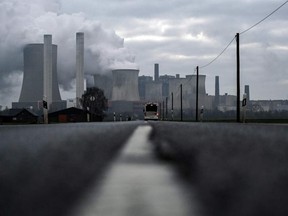 In this file photo taken on Jan. 17, 2022, a bus drives on a road as steam rises from the cooling towers of the lignite-fired power plant of German energy giant RWE in Niederaussem, western Germany.