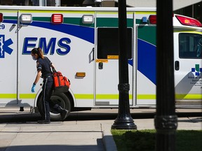 A Calgary paramedic carries equipment back to an ambulance during a downtown call on June 11, 2022.