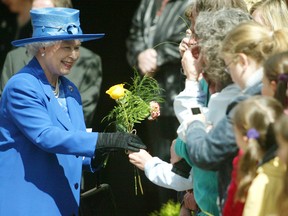 Onlookers offer flowers to Queen Elizabeth II as she exits the Anglican Church of St. Mary and St. George in Jasper on May 21, 2005. Calgary Herald archives