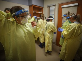 Nurses prepare to treat a COVID-19 patient in an intensive care unit at Peter Lougheed Centre on Nov. 14, 2020.