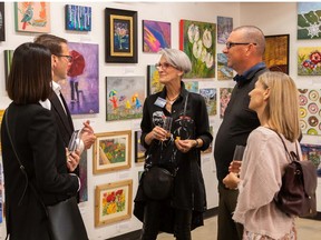 Artist Heather MacPherson shows her work to guests at a reception for the Art is the Heart of the Home program. Artists have donated work to an affordable housing project. Photo, Leonardo Jenkins
