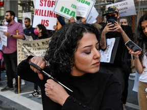 A woman cuts her hair during a protest against the Islamic regime of Iran and the death of Mahsa Amini in New York City, New York, U.S., September 27, 2022.