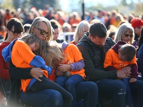 Jessiya Rider holds daughters Heidi and Lucy and Justin Rider holds son Felix during a moment of prayer at Fort Calgary.