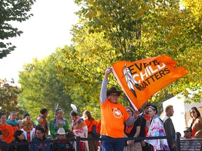 A flag is hoisted during Orange Shirt Day ceremonies at Fort Calgary.