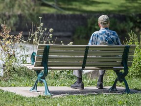 A senior sits on a bench by the Humber River in Toronto.