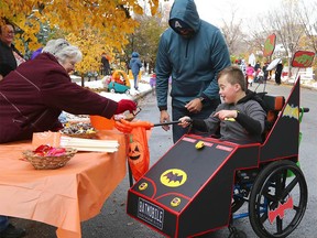 Dad Gabe Girimonte with Sebastian, 9, as they receive a treat during an accessible and inclusive trick-or-treating experience for children with disabilities on 10A St. NW in Kensington in Calgary on Sunday, October 23, 2022.